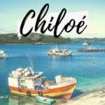 Vue de bateaux dans un port de Chiloé, ciel clair et eaux bleues.