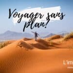 Personne debout sur une dune de sable dans un désert, montagnes en arrière-plan.