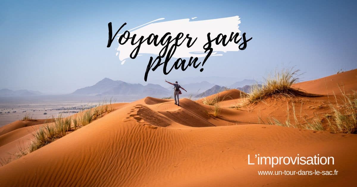 Personne debout sur une dune de sable dans un désert, montagnes en arrière-plan.