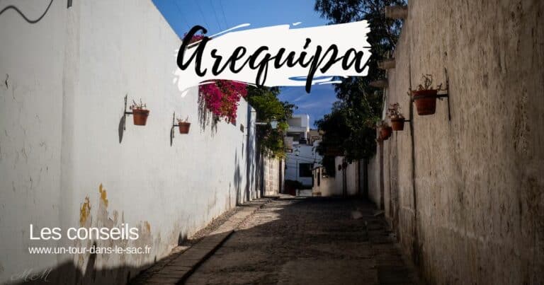 Rue étroite avec murs blancs et pots de fleurs suspendus à Arequipa.