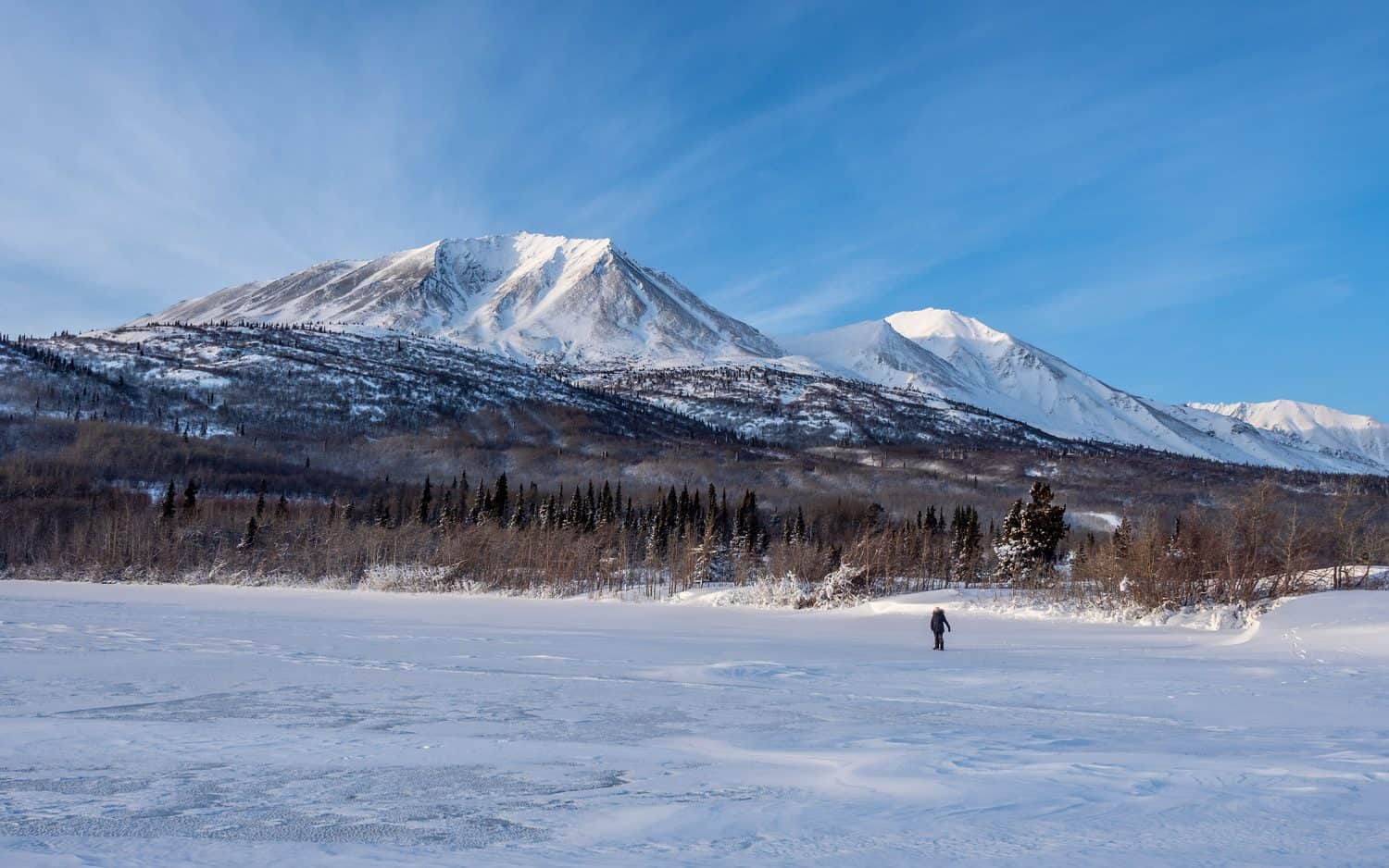 Montagnes enneigées et lac gelé dans le Yukon en hiver.