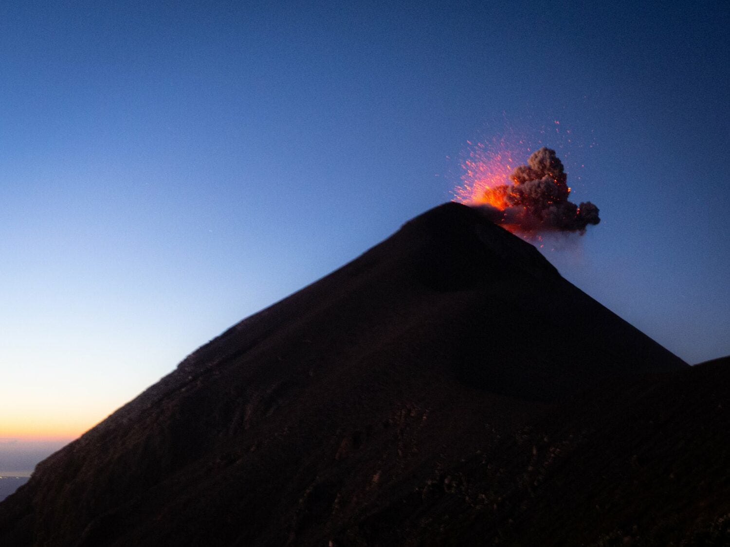 Explosion du volcan Fuego projetant de la lave à l’heure bleue, vue depuis l’Acatenango