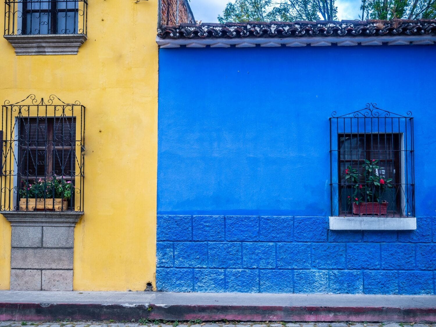 Façades jaune et bleue aux fenêtres grillagées dans une rue d’Antigua Guatemala