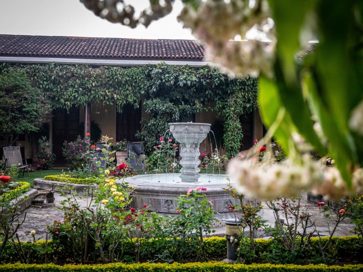 Jardin fleuri et fontaine du patio de l’Hotel Aurora à Antigua Guatemala
