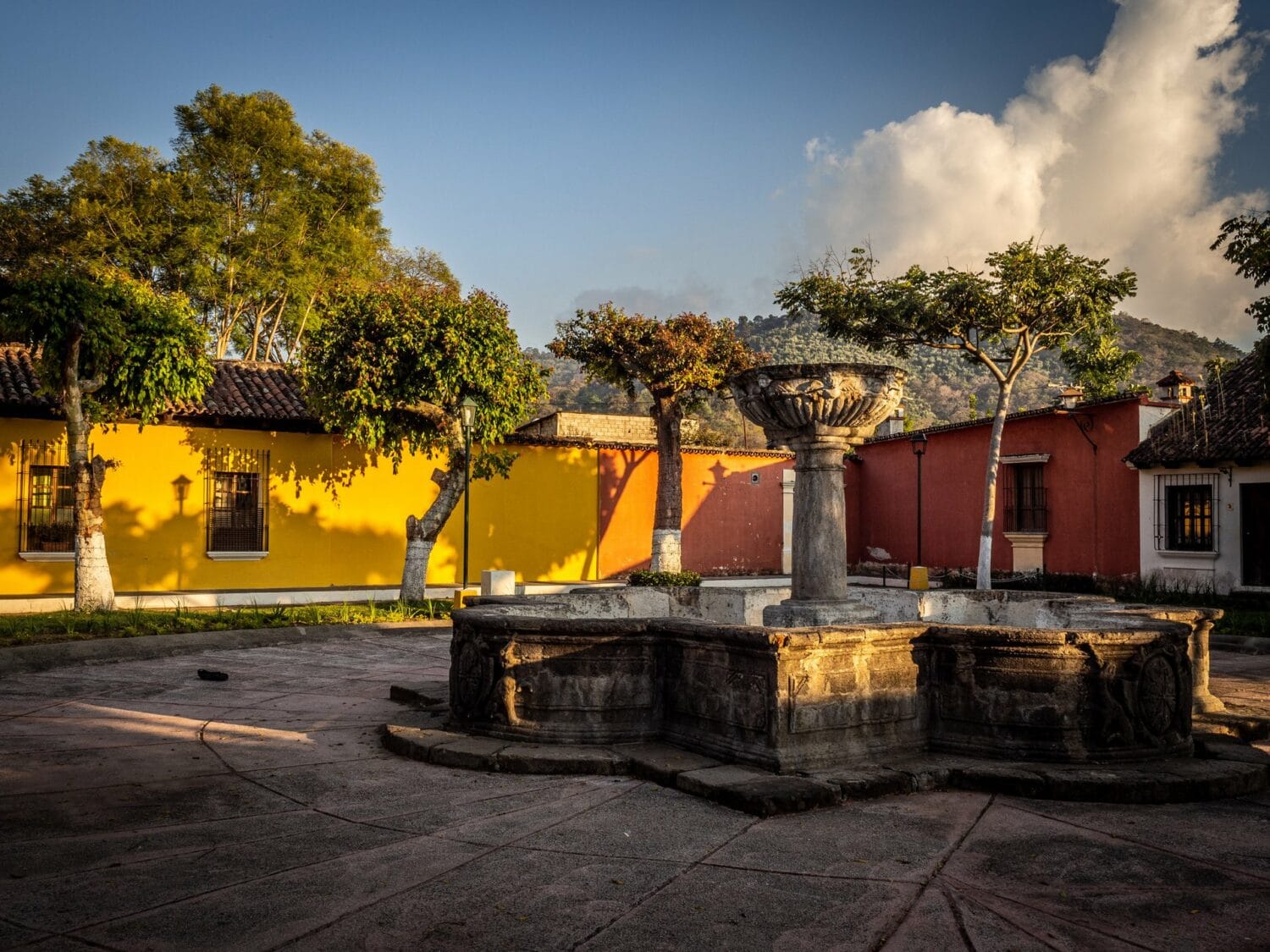 Fontaine de pierre de la Pila de Rubio entourée de maisons jaunes et rouges à Antigua Guatemala