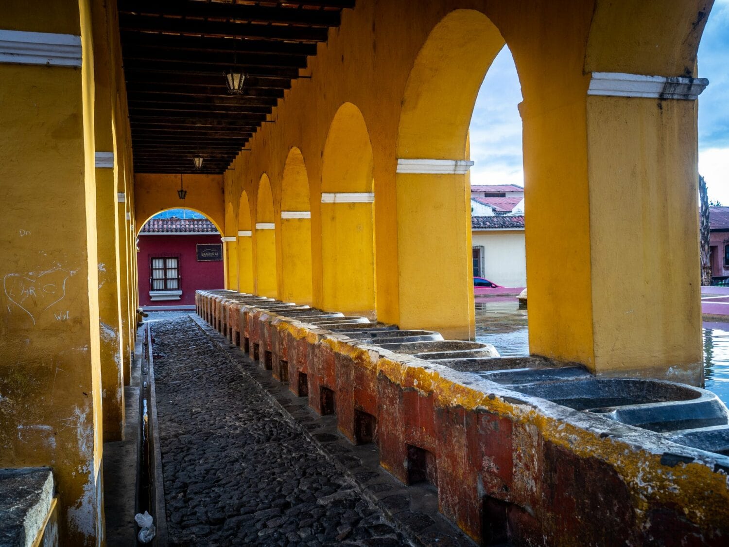 Arcades jaunes et bacs de pierre du lavoir Tanque de la Unión à Antigua