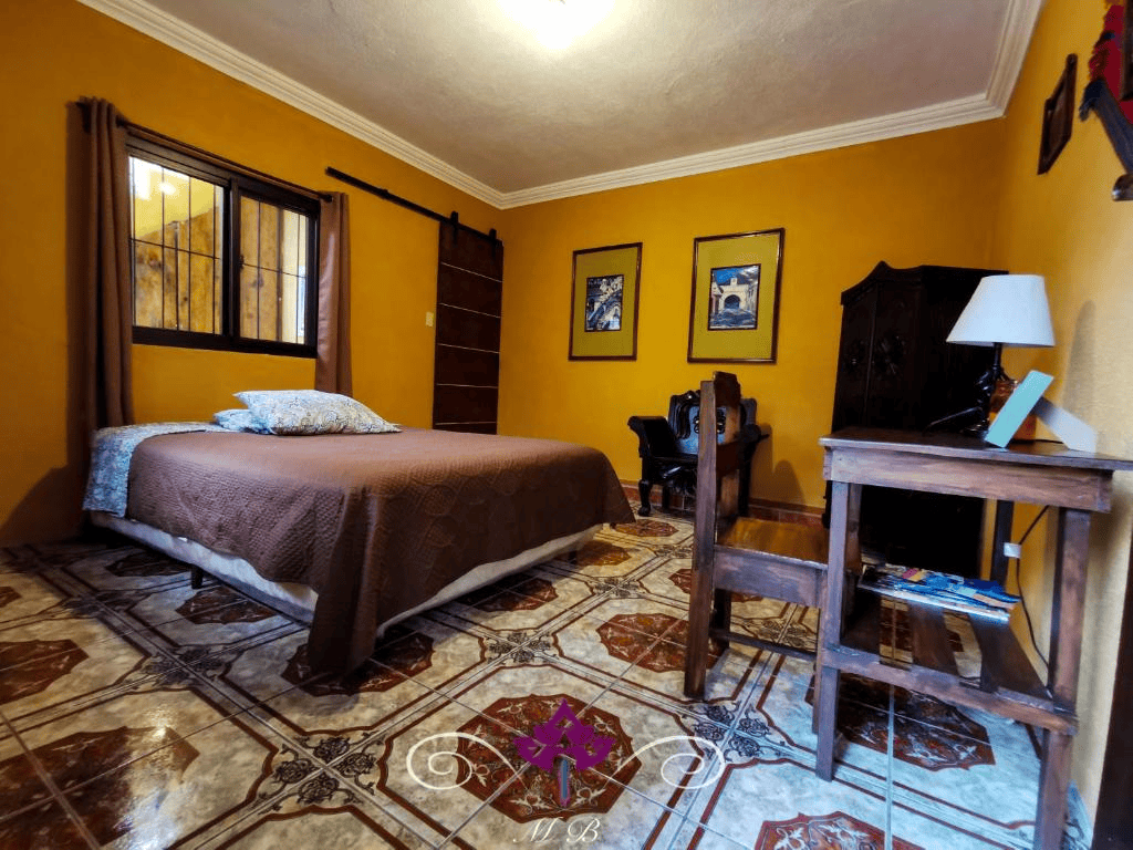 Chambre avec murs jaunes, lit, bureau et décorations murales.