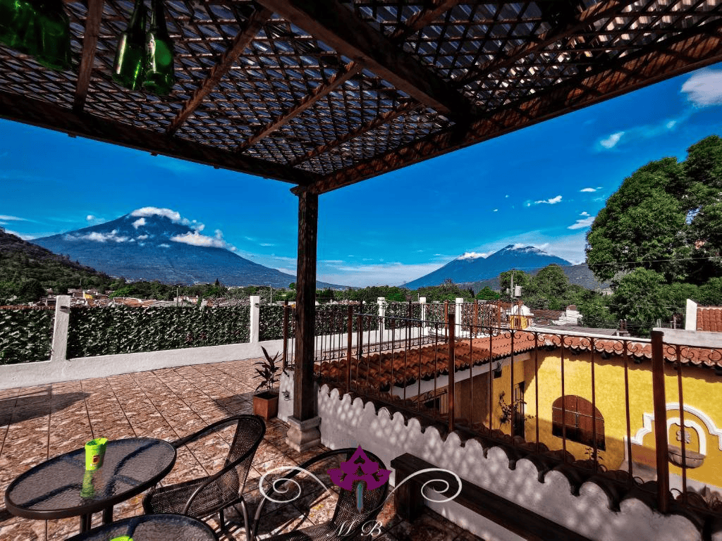 Vue sur Antigua Guatemala avec volcans en arrière-plan depuis une terrasse.