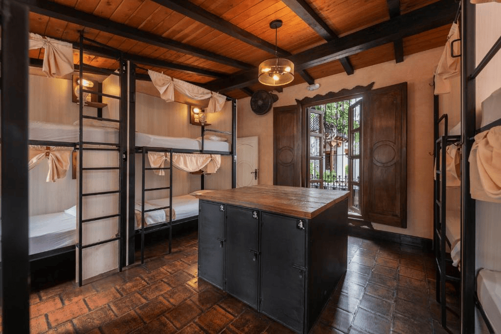 Chambre avec lits superposés en bois et mobilier vintage, fenêtre ouverte.